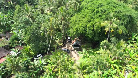 travel minivan drives on narrow sidemen village road in tropical jungle of bali indonesia, aerial flyover