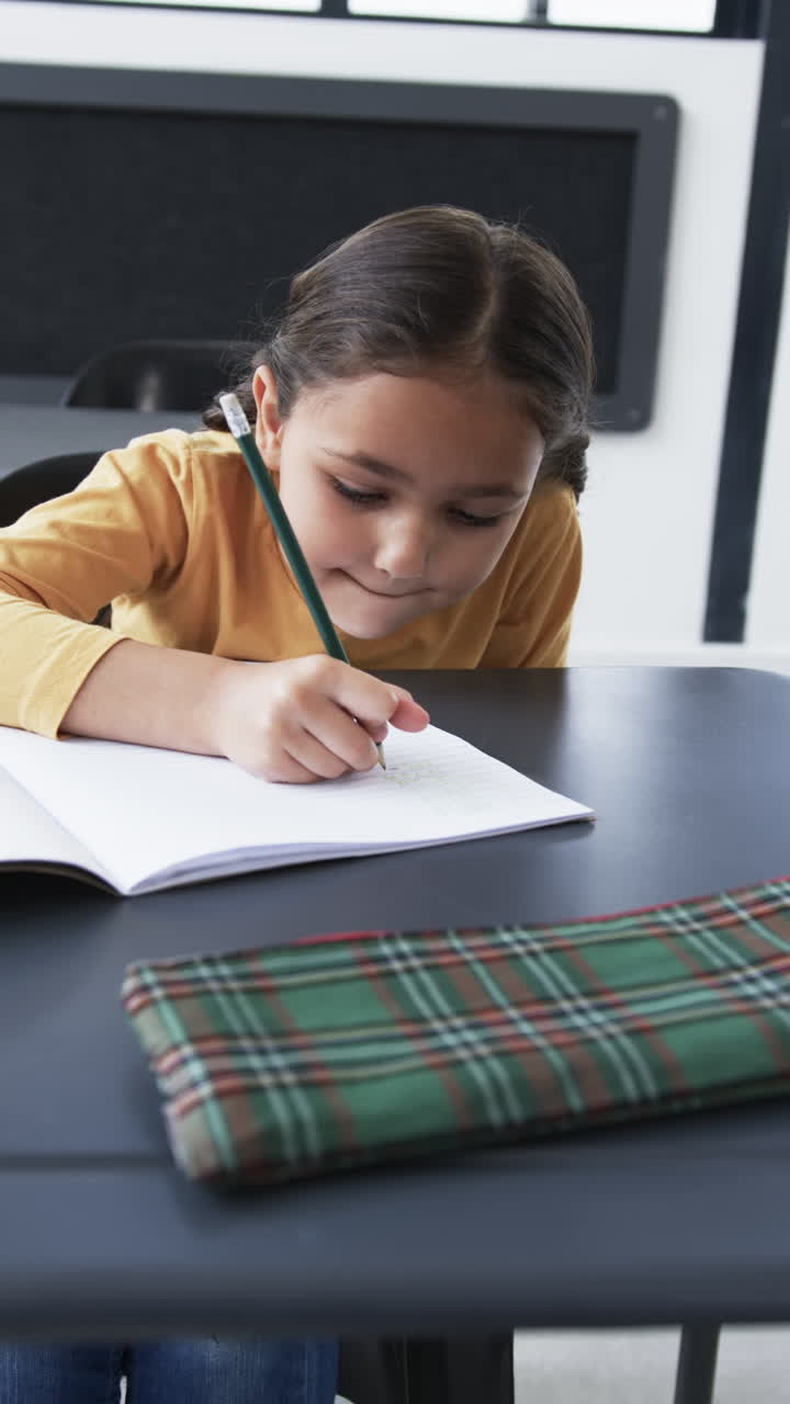 Vertical video: In a school setting, a young biracial student is focused on writing