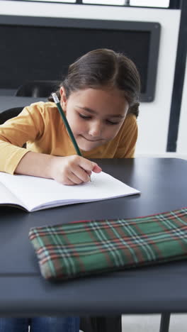 vertical video: in a school setting, a young biracial student is focused on writing