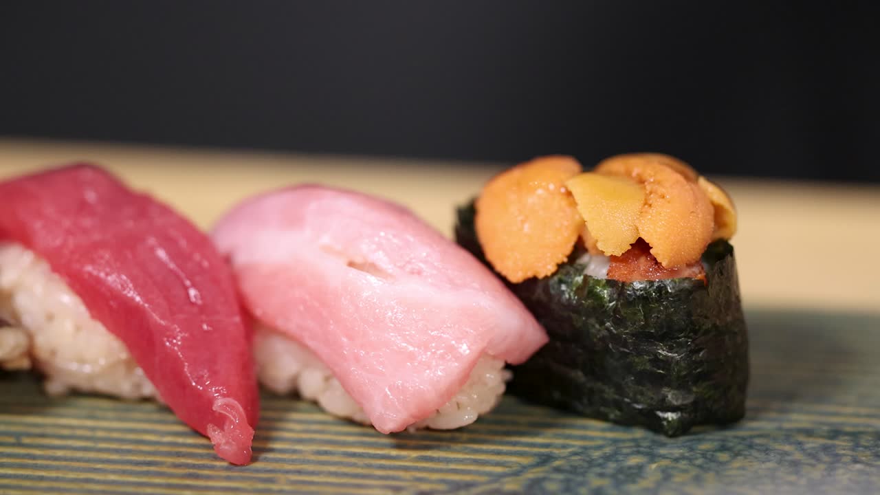 Nahaufnahme von Premium-Thunfisch-Nigiri und Seeigel-Gunkan-Sushi auf einem traditionellen Holzbrett