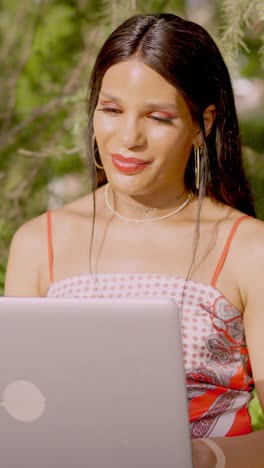 woman smiling and working on a laptop outdoors