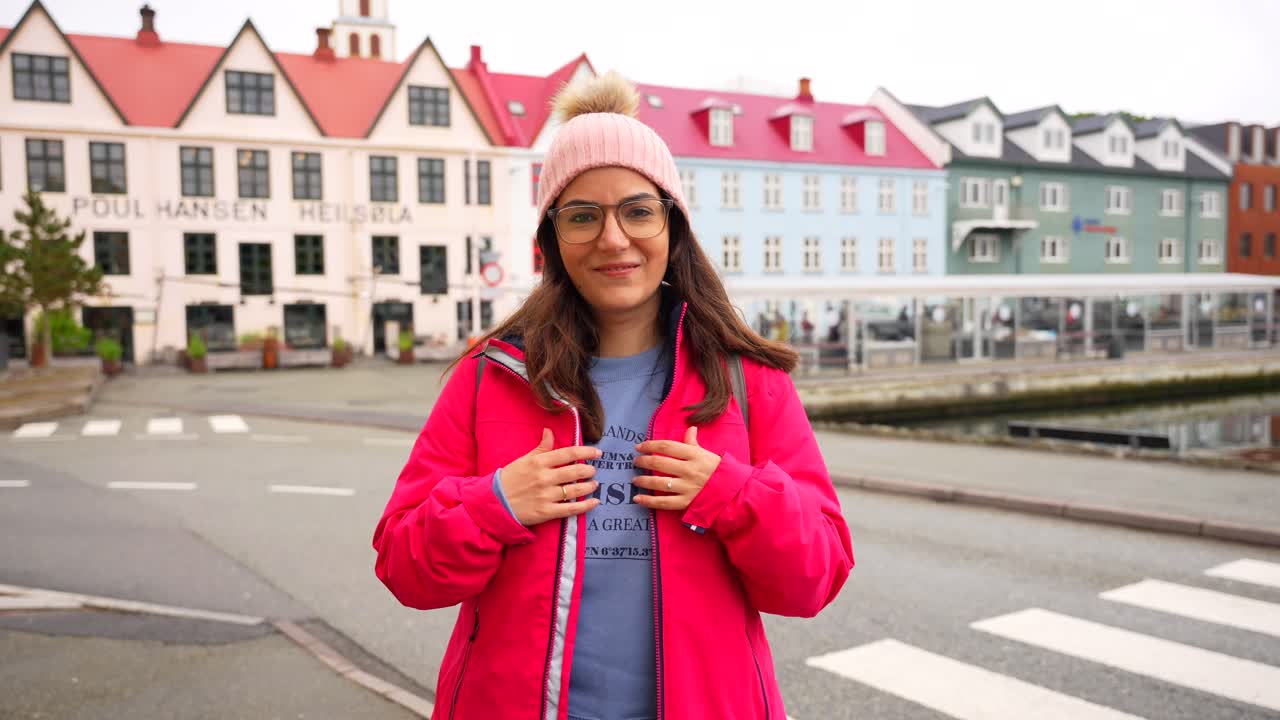 Giovane donna felice mostra una maglietta delle Isole Faroe con la pittoresca città di Torshavn sullo sfondo
