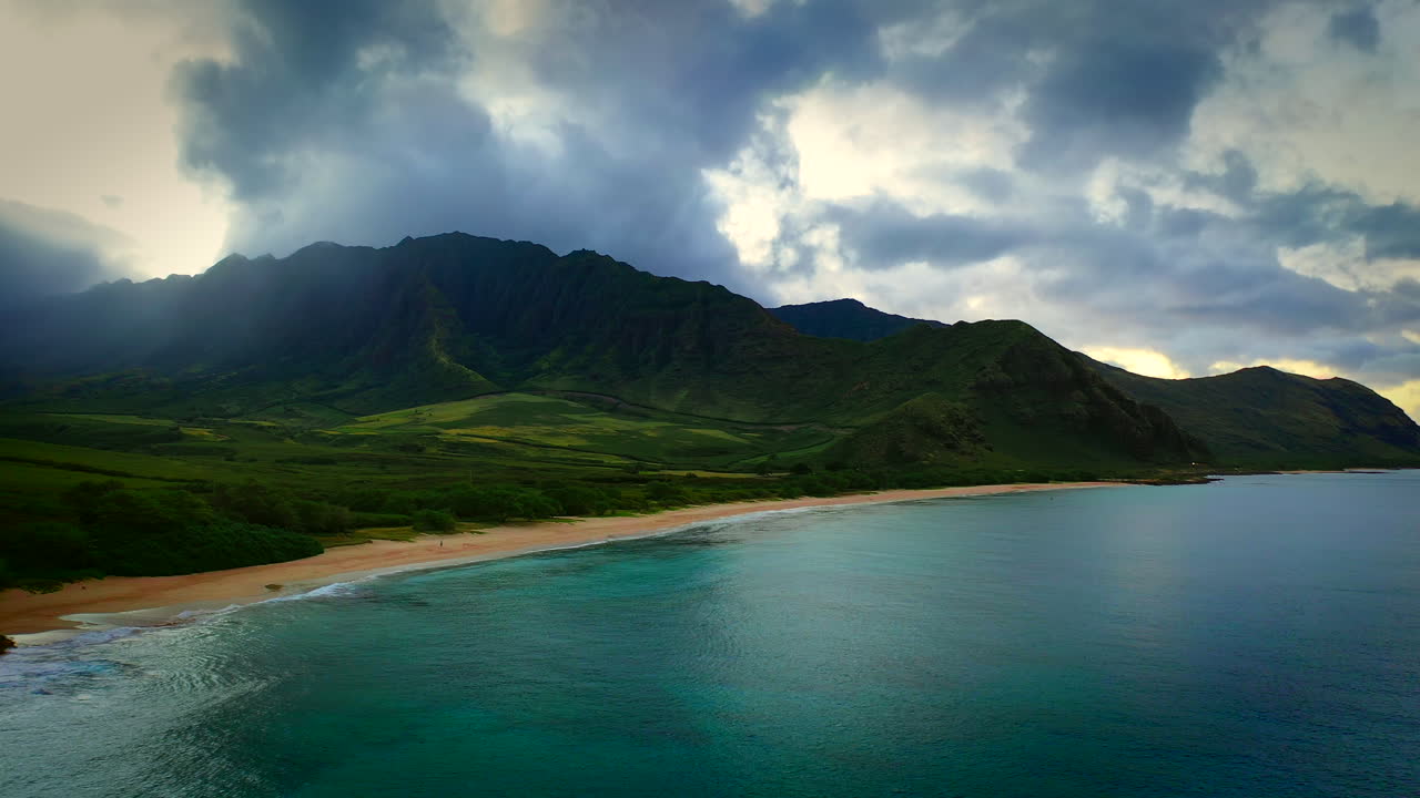 Man alone on amazing beach with dramatic ridges in background, aerial, Oahu