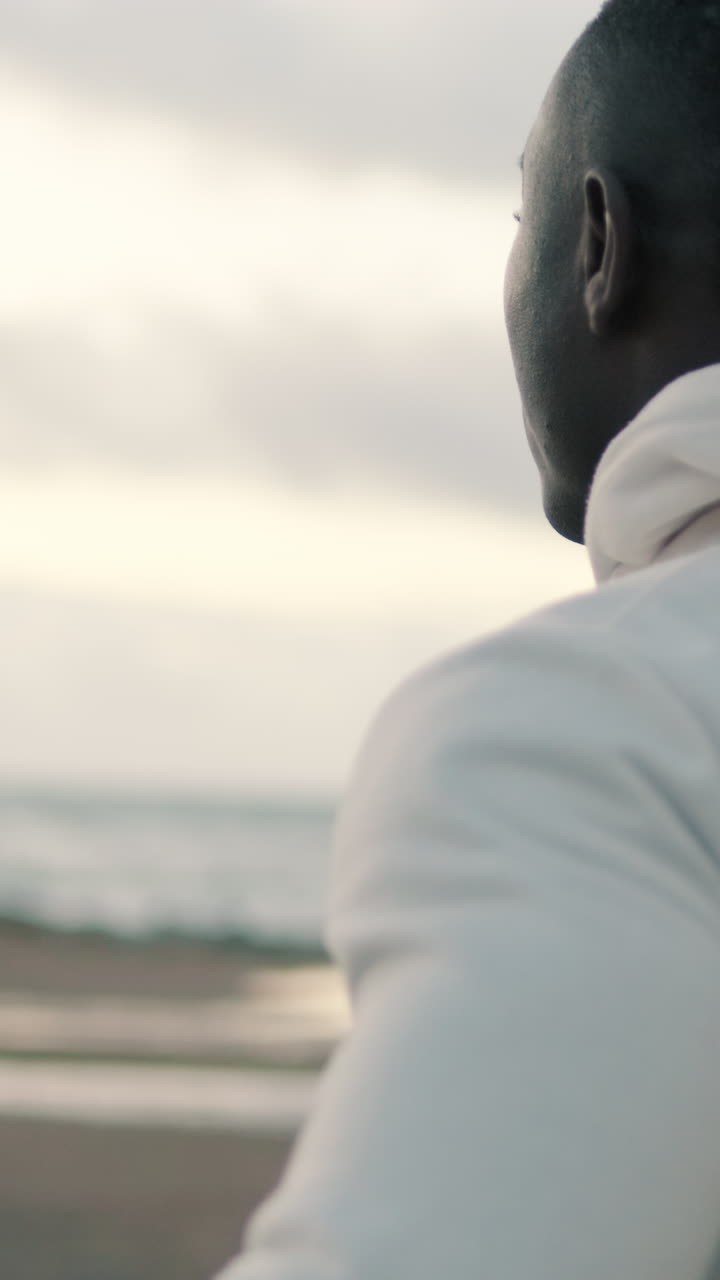Giovane uomo nero che si abbassa il cappuccio della felpa in spiaggia