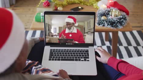 African-american-mother-and-daughter-using-laptop-for-christmas-video-call-with-santa-on-screen