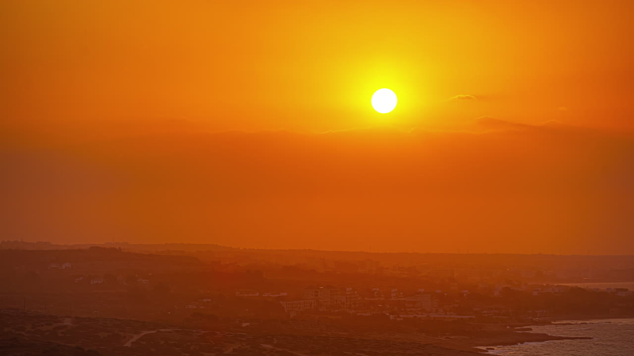 A bright yellow sun emerges from an orange glow behind the clouds