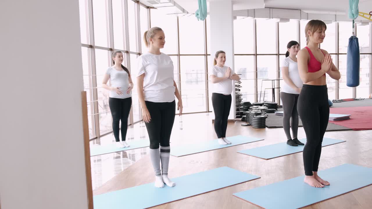 mujeres haciendo ejercicios de estiramiento en un gimnasio moderno con un instructor