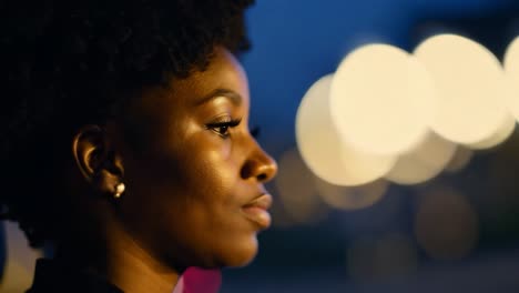 young businesswoman rides in a car at night, gazing out at the vibrant city lights and reflecting on her journey