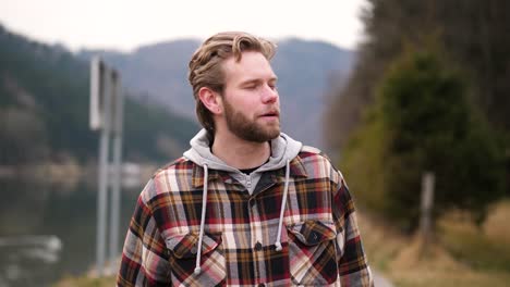 a-hearty-laugh-of-a-young-man-walking-along-a-path-next-to-a-river-whitewashes-this-video-in-an-autumn-landscape