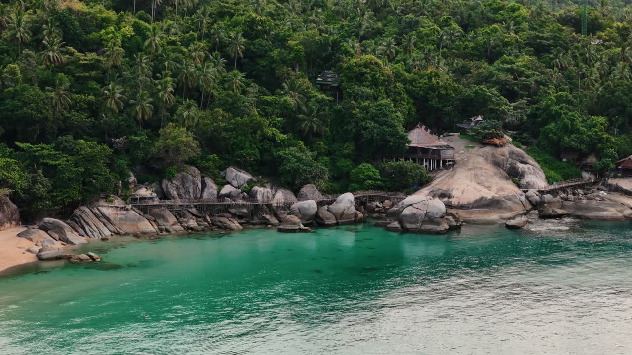 Aerial view of tropical beach, large rocks and jungle coastline in Thailand. Turquoise water, lush greenery, and unique rock formations create a perfect travel and nature scene.
