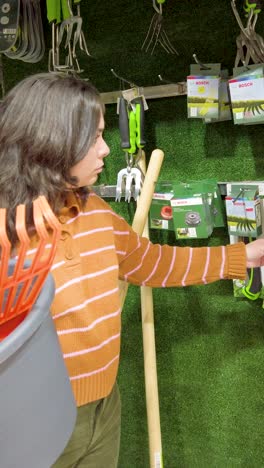 woman choosing gardening tools in hardware store