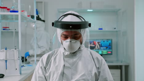 chemist in coverall looking up at video camera sitting in lab