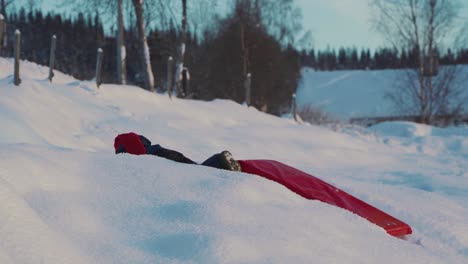 Tracking-shot-of-male-kid-pulling-up-sled-in-deep-icy-snow-during-sunny-day,close-up