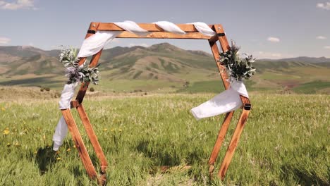 Ceremonia-De-Boda-Arco-Hexagonal-Hecho-De-Madera-Cubierto-De-Flores-Y-Lino-Blanco-Que-Sopla-En-El-Viento-En-Las-Montañas-De-Idaho-Para-Una-Pequeña-Fuga-1080p-60fps