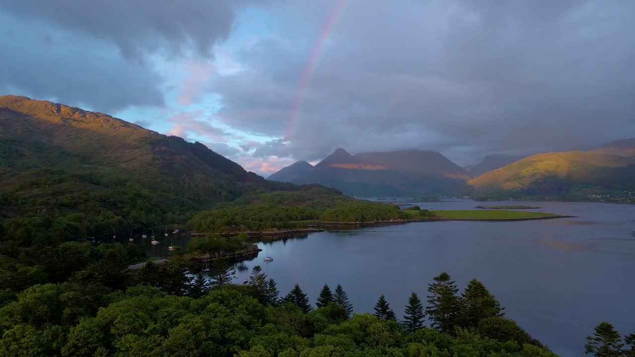 imágenes aéreas de drones de 4k de acercar un arco iris en un cielo nublado con barcos en el agua en las tierras altas escocesas de escocia al atardecer