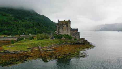 Aerial-pan-around-the-famous-Scottish-Castle,-Eilean-Donan,-on-a-cloudy-autumn-day-in-the-Scottish-highlands,-Scotland,-United-Kingdom