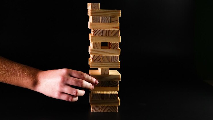 Hand removing block from wooden tower