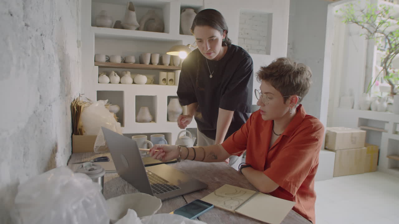 Artista donna che discute di un progetto con un collega in uno studio di ceramica