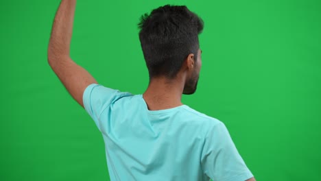 vista trasera inspirada hombre de oriente medio agitando bandera alemana apoyando al equipo de fútbol en el campeonato. motivado confiado joven fan regocijándose animando en el fondo de pantalla verde chromakey.