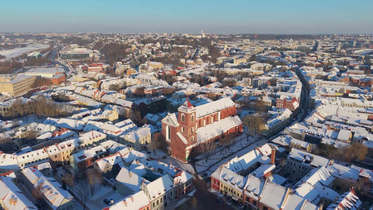 Záběr z dronu na Katedrální baziliku v Kaunasu v historickém Starém Městě Kaunas v Litvě, představující malebnou, sněhem pokrytou městskou krajinu pod jasnou oblohou.