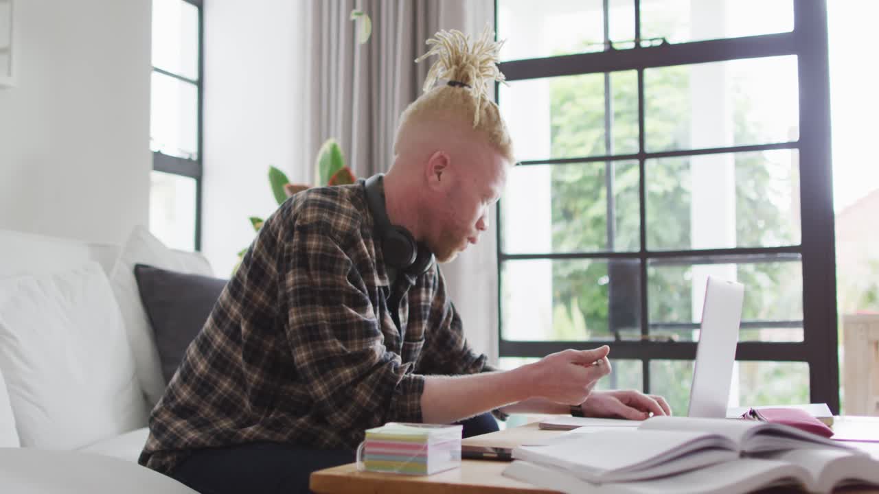 Albino african american man with dreadlocks working and using laptop