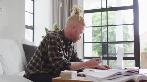 albino african american man with dreadlocks working and using laptop