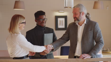 cheerful business people shaking hands and speaking in restaurant