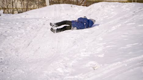 child boy having fun, rolls head over hills. playing and laughing on snowy winter walk in nature. frost winter season.cute little boy with having fun outdoors on winter day. ride down a hill, winter games and fun