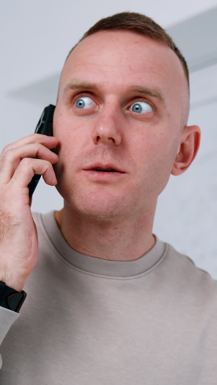 Caucasian man answering the phone call. Surprised man speaking on the smartphone and looks at his gadget with astonishment