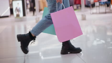 vista lateral de una persona caminando sobre azulejos elegantes con reflejos de luz, sosteniendo una bolsa de compras en una tienda minorista, las características de fondo muestran ropa con iluminación borrosa