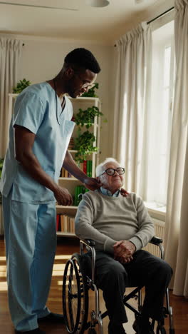 caregiver assists elderly man in wheelchair at home