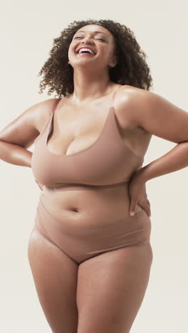 vertical video: smiling plus size woman in underwear posing confidently, embracing body positivity