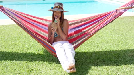 mujer bebiendo una bebida de coco en una hamaca