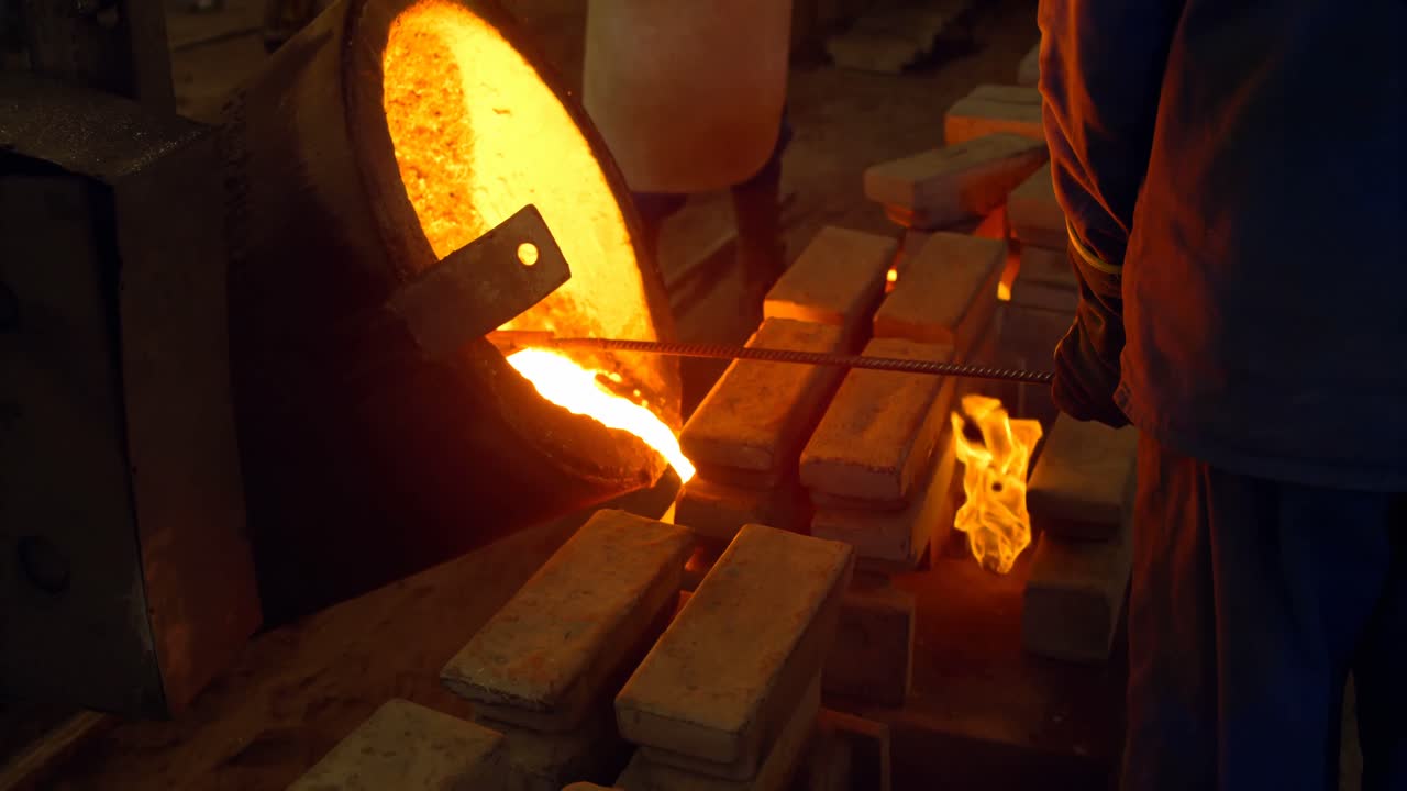 trabajador masculino vertiendo metal fundido en el molde en el taller 4k