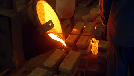 male worker pouring molten metal in mold at workshop 4k