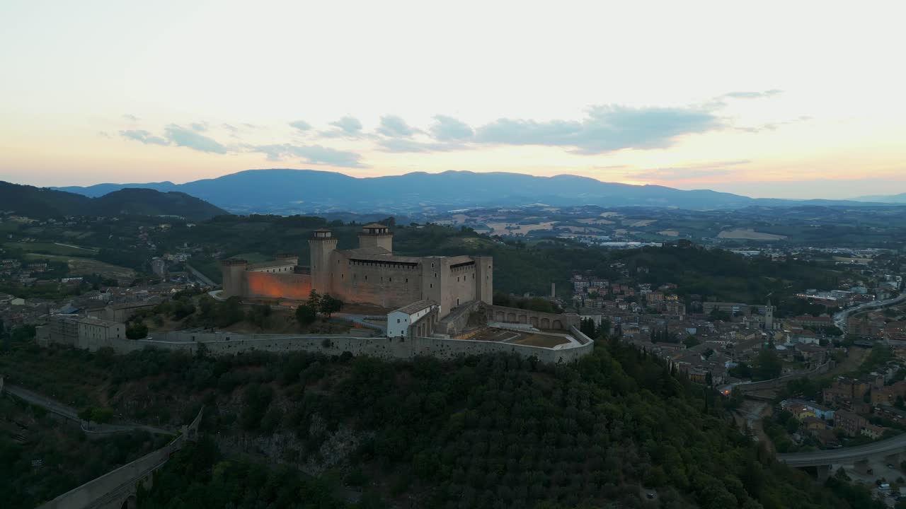 vista aérea de la fortaleza iluminada de rocca albornoziana en la ladera con vistas a la ciudad de spoleto durante la hora dorada