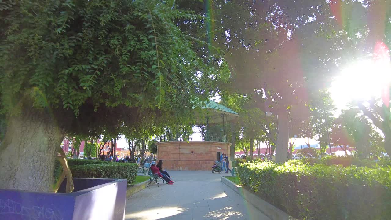 People gathering near the kiosk at the downtown city square wearing masks during the pandemic. Happy family leisure moments. Latin-america