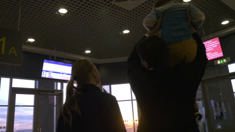 familia en la terminal del aeropuerto mirando hacia afuera al atardecer