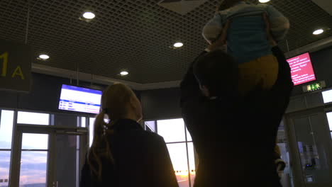 family at airport terminal looking outside at sunset