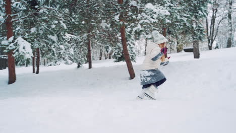 little girl is running in the snow and falling into it in winter. side view of a child who is having fun in cold season outdoors. slow motion.