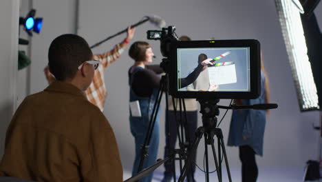 female production assistant uses clapperboard as actors shoot movie or video in studio with film crew and director 1