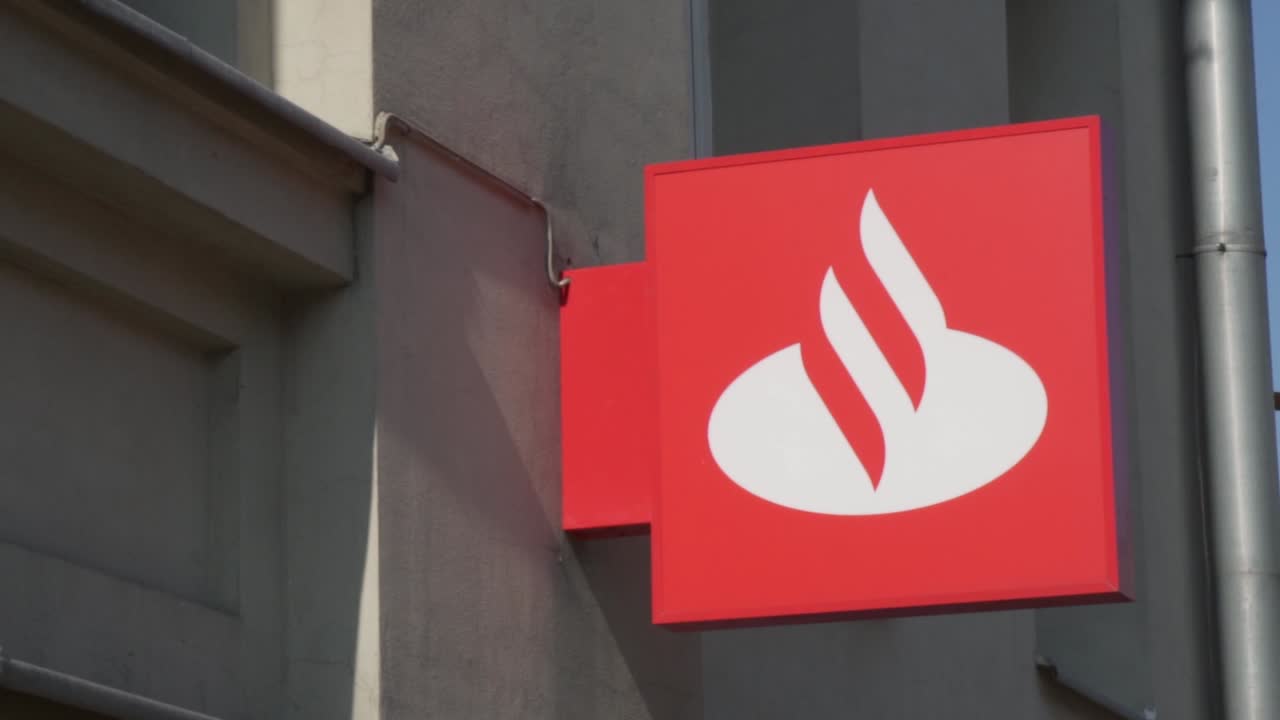 Pan slow motion shot of the Santander bank sign in the street.