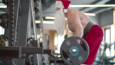 athlete man having fun at gym. sporty guy in santa costume making repetitions