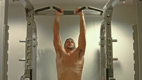 Fit-man-doing-pull-ups-in-fitness-studio