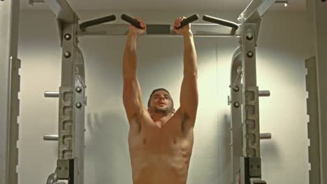 fit man doing pull ups in fitness studio