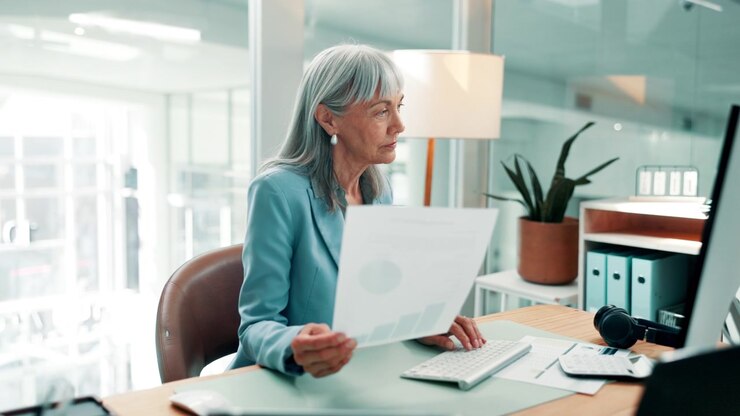 Mature Businesswoman Reviewing Financial Documents in Modern Office