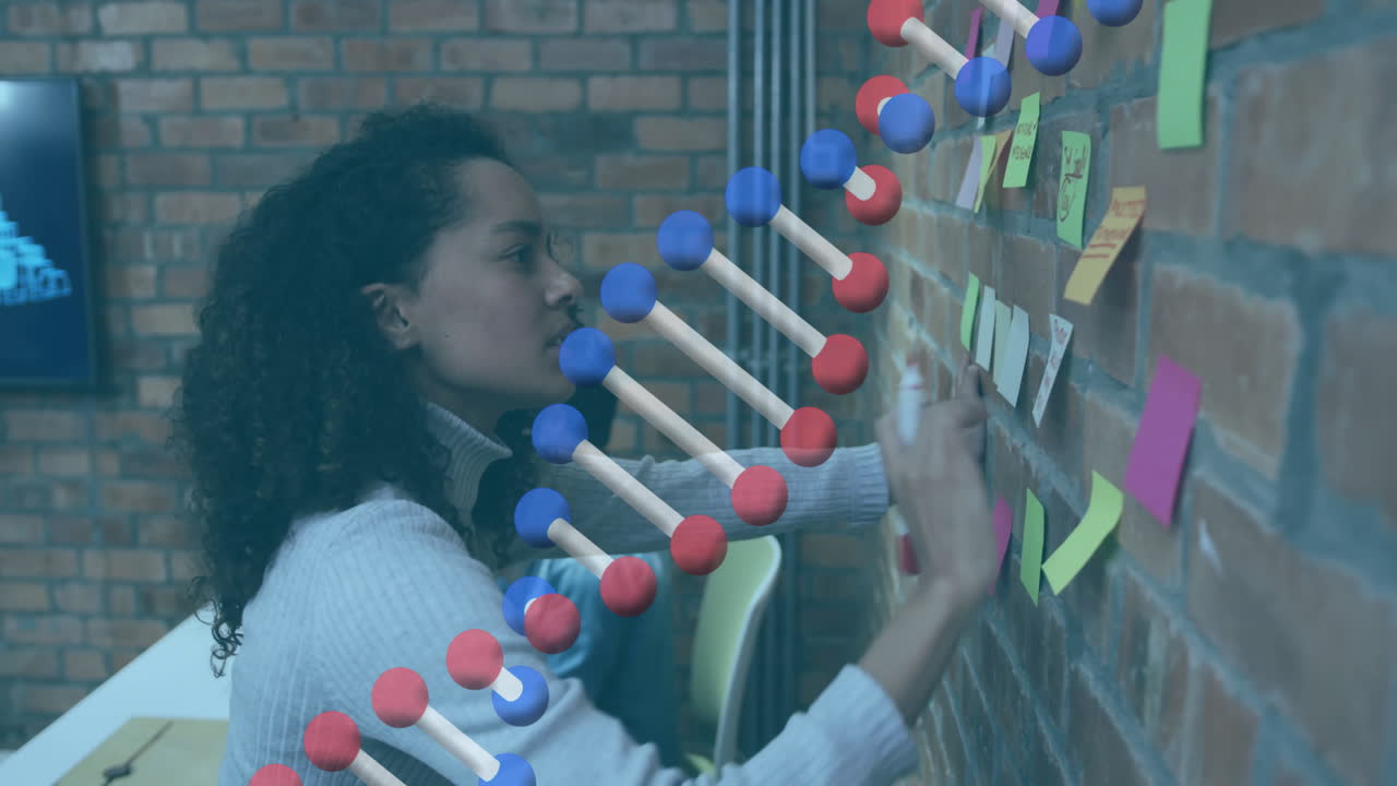 Woman writing on sticky notes with DNA strand animation over brick wall