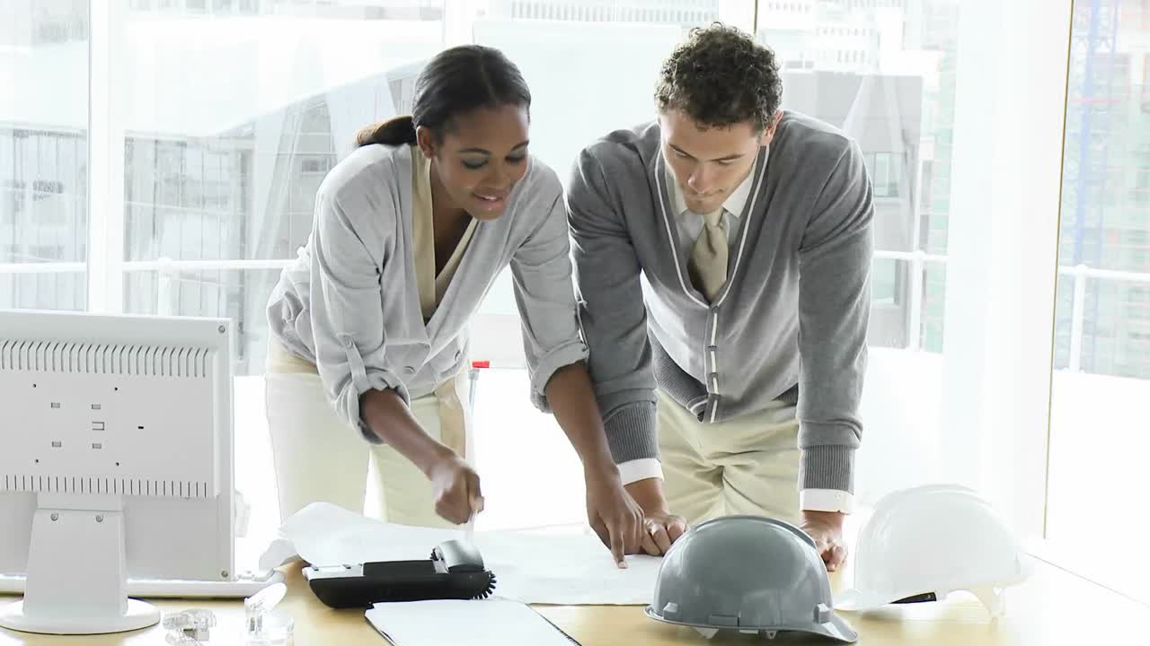 jóvenes arquitectos estudiando planos