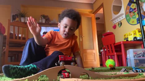 very expressive and funny 3-year-old black child playing at home with his toy train