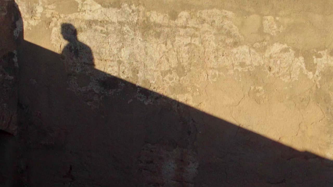 오렌지색의 옛 벽에 그늘이 걸어가는 아만